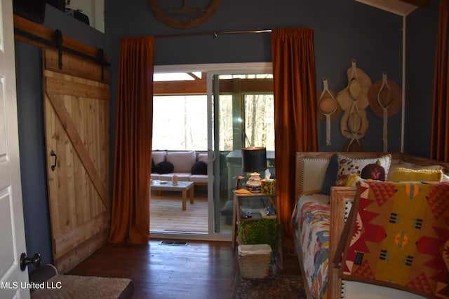 interior space with visible vents, a barn door, and hardwood / wood-style flooring