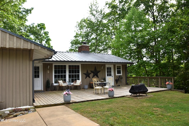 back of house featuring a lawn, a chimney, a deck, and metal roof