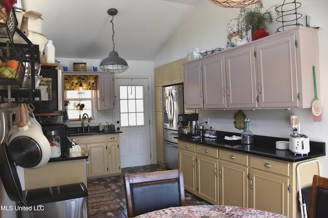kitchen featuring dark countertops, stainless steel fridge, a sink, lofted ceiling, and pendant lighting