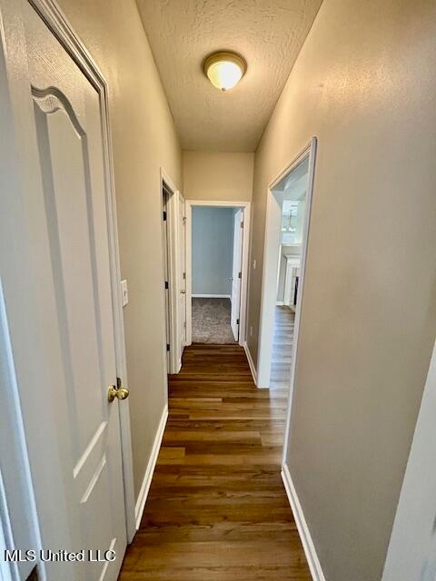 hallway with a textured ceiling and dark hardwood / wood-style floors