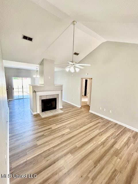 unfurnished living room featuring lofted ceiling, a tile fireplace, light hardwood / wood-style floors, and ceiling fan