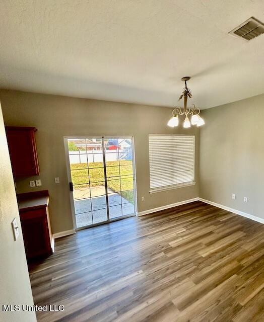 unfurnished dining area featuring hardwood / wood-style flooring and a chandelier