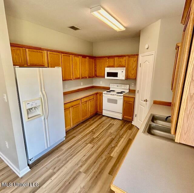 kitchen featuring light hardwood / wood-style flooring, sink, and white appliances