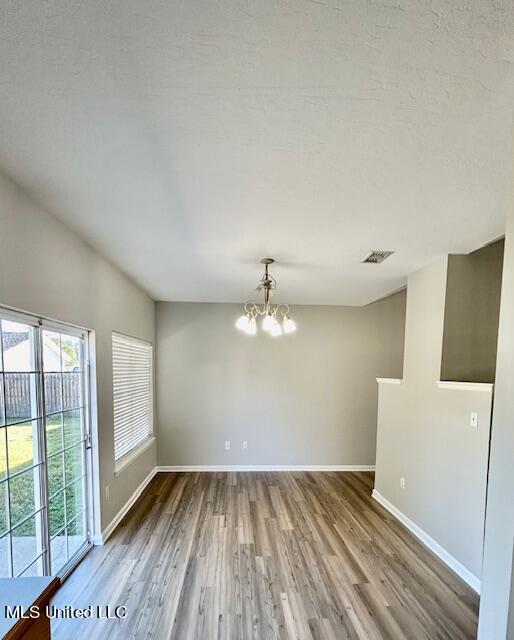 empty room with a notable chandelier and hardwood / wood-style floors