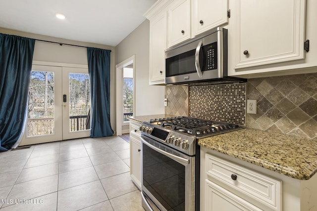 kitchen with stainless steel appliances, french doors, white cabinetry, and light stone countertops