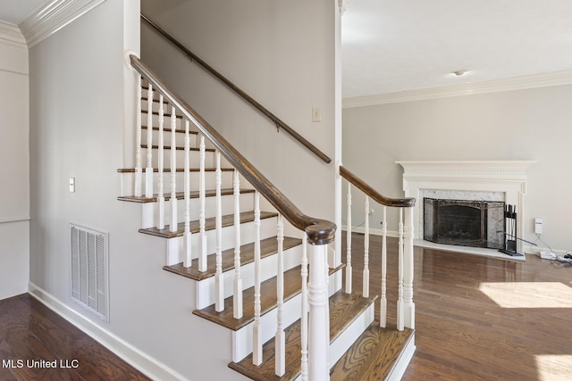 stairway featuring crown molding, hardwood / wood-style floors, and a high end fireplace