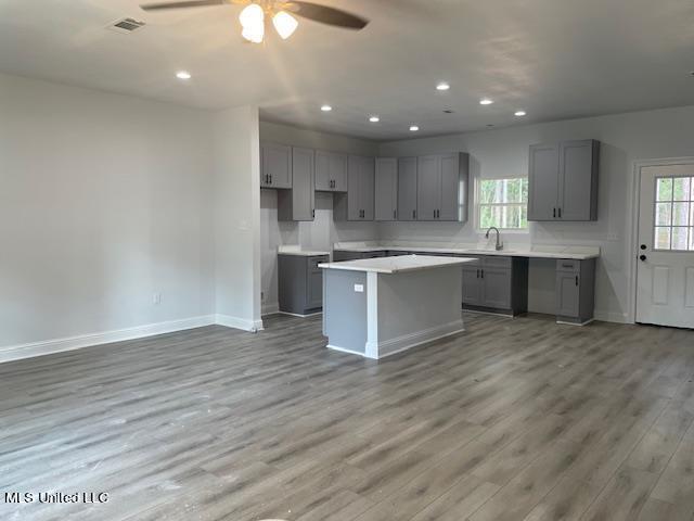 kitchen with a kitchen island, ceiling fan, gray cabinetry, and hardwood / wood-style flooring