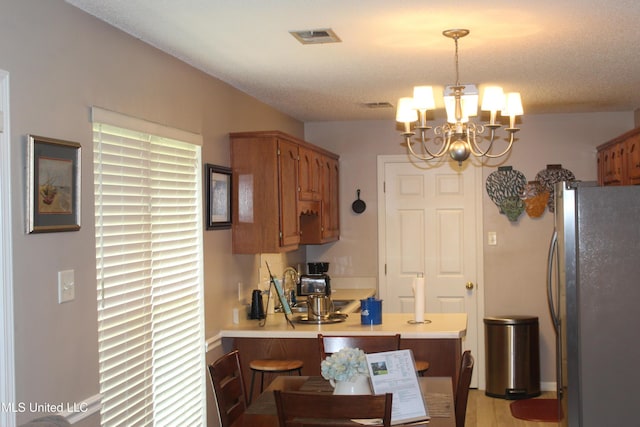 100 Roseleigh Cv, Batesville, MS 38606 - kitchen featuring freestanding refrigerator, a chandelier, brown cabinetry, light countertops, and a peninsula