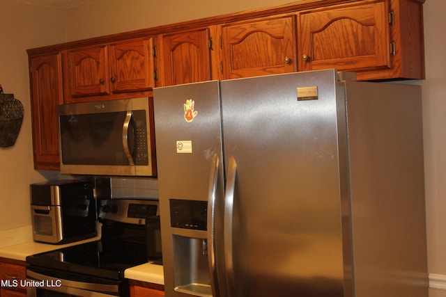100 Roseleigh Cv, Batesville, MS 38606 - kitchen featuring appliances with stainless steel finishes, brown cabinetry, light countertops, and decorative backsplash