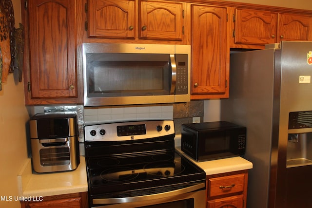100 Roseleigh Cv, Batesville, MS 38606 - kitchen featuring appliances with stainless steel finishes, decorative backsplash, light countertops, and brown cabinetry