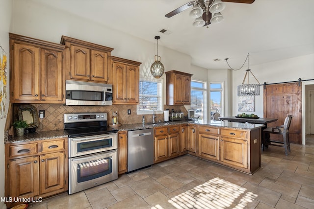 kitchen with appliances with stainless steel finishes, a barn door, decorative light fixtures, and ceiling fan