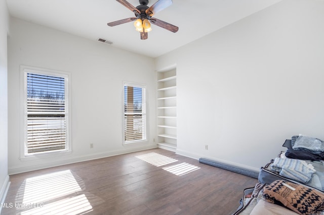 empty room featuring hardwood / wood-style floors, ceiling fan, and built in features