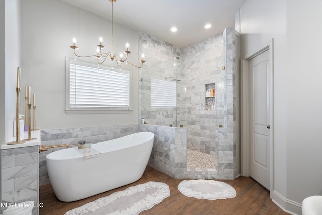 bathroom with plus walk in shower, hardwood / wood-style flooring, and a notable chandelier