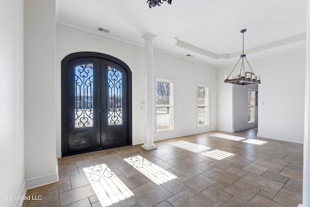 entrance foyer with an inviting chandelier, ornamental molding, french doors, and a tray ceiling