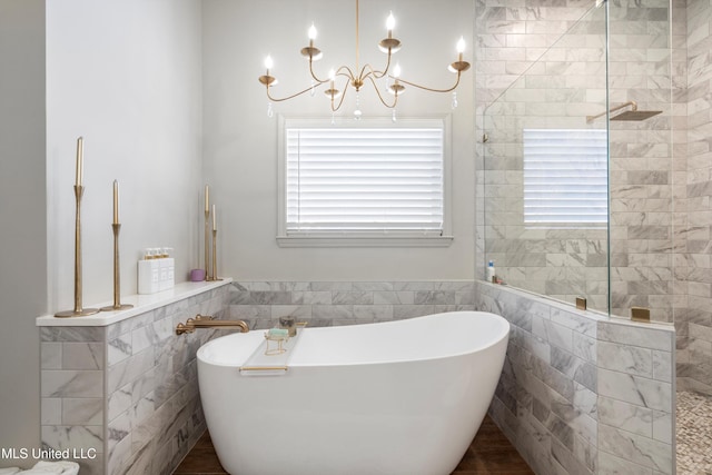 bathroom featuring a bath, tile walls, and an inviting chandelier