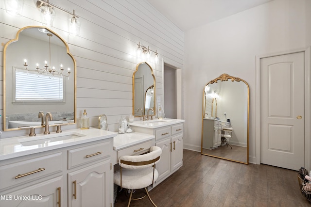 bathroom featuring hardwood / wood-style flooring, vanity, wood walls, and a notable chandelier