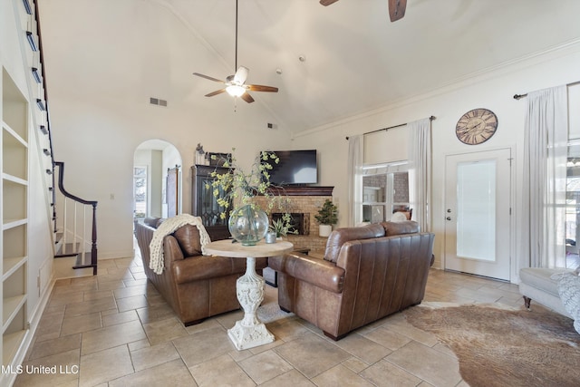 living room featuring ceiling fan, high vaulted ceiling, and a brick fireplace