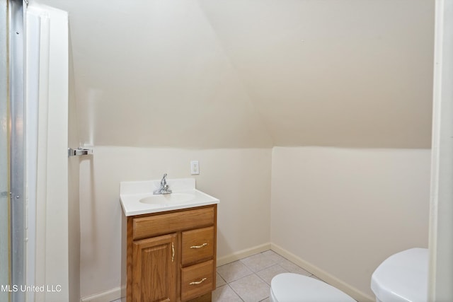 bathroom with tile patterned floors, vanity, vaulted ceiling, and toilet