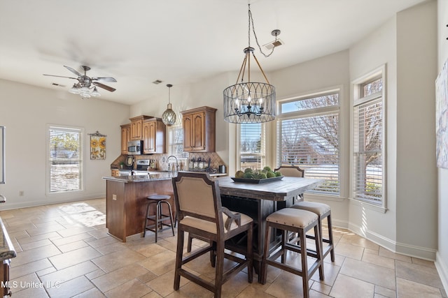 dining space featuring sink and ceiling fan with notable chandelier