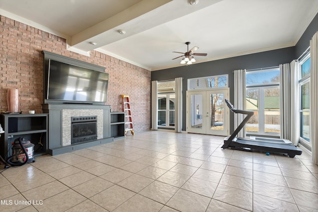 unfurnished living room with a tile fireplace, french doors, ceiling fan, light tile patterned floors, and brick wall