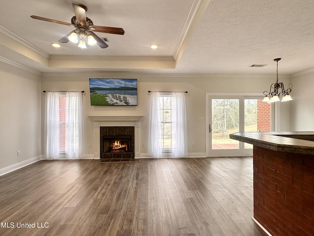 unfurnished living room featuring a tray ceiling, a healthy amount of sunlight, dark wood-style flooring, and visible vents