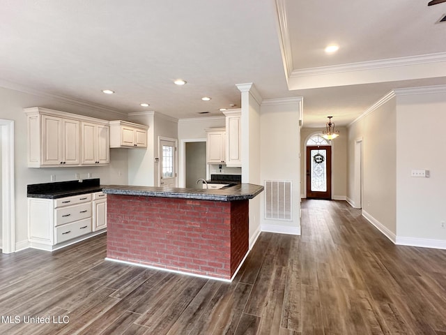 kitchen with dark countertops, visible vents, a peninsula, and dark wood-style floors