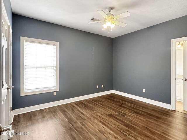 empty room with visible vents, ceiling fan, baseboards, and dark wood-style flooring