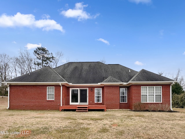 back of property featuring brick siding, a yard, and roof with shingles