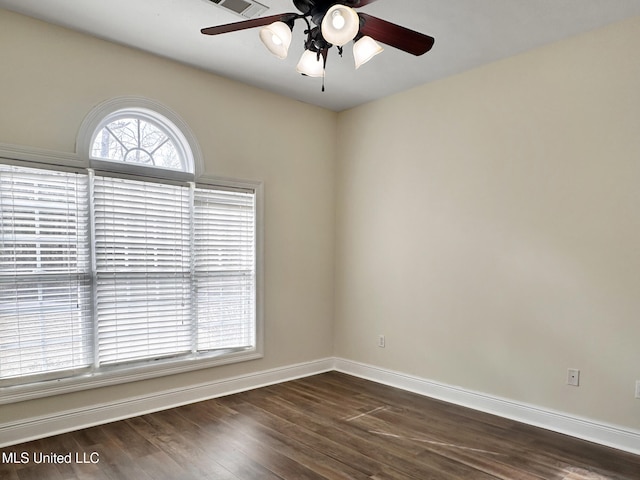 empty room featuring dark wood finished floors, a ceiling fan, and baseboards