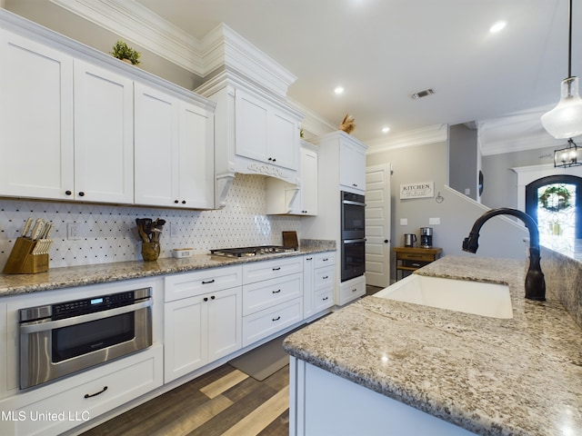 kitchen featuring white cabinetry, sink, stainless steel gas cooktop, pendant lighting, and decorative backsplash