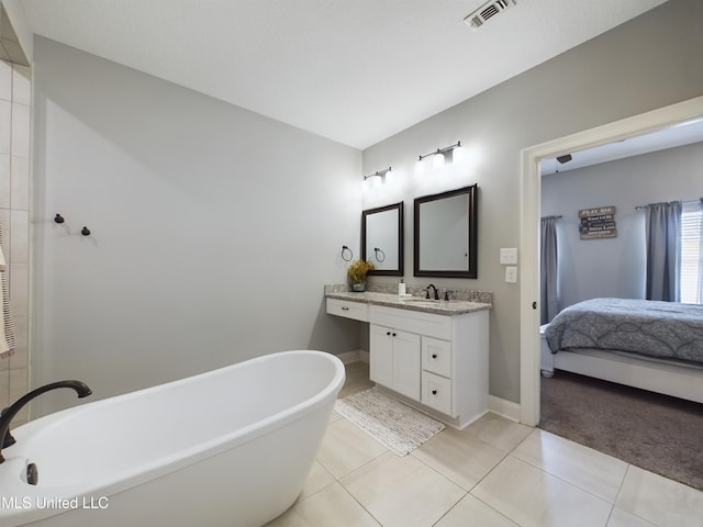 bathroom with a washtub, vanity, and tile patterned floors