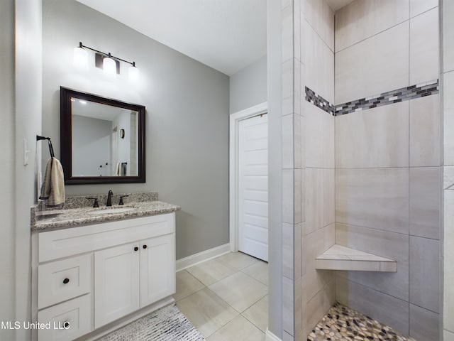 bathroom featuring a tile shower, tile patterned flooring, and vanity