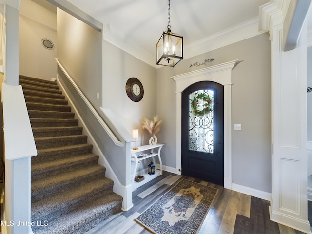 entryway with hardwood / wood-style floors, crown molding, and a notable chandelier