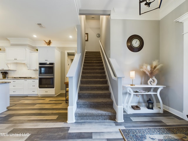 stairway featuring hardwood / wood-style floors and ornamental molding