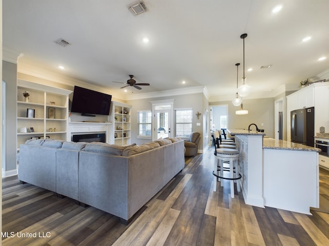 living room featuring ceiling fan, dark hardwood / wood-style flooring, and ornamental molding