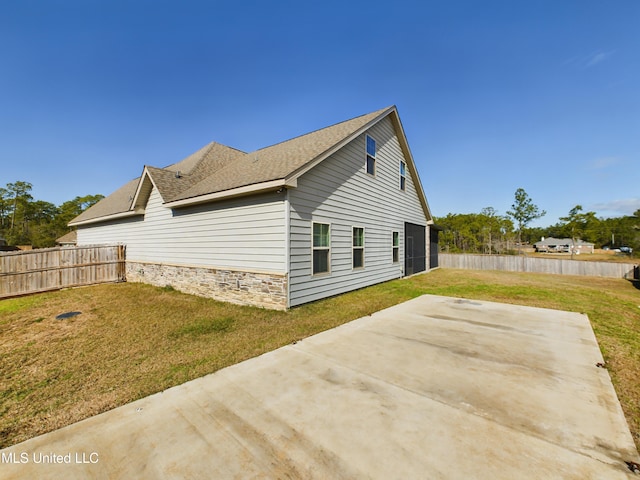 view of side of home with a lawn and a patio