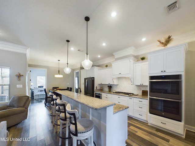 kitchen featuring a kitchen breakfast bar, light stone countertops, white cabinetry, and appliances with stainless steel finishes