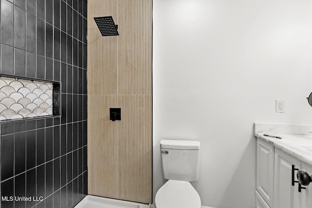 bathroom with vanity, toilet, and a tile shower