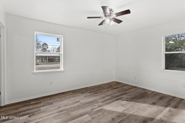 unfurnished room featuring hardwood / wood-style flooring, a wealth of natural light, and ceiling fan