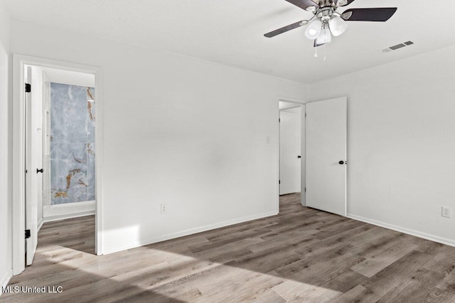 unfurnished bedroom with connected bathroom, hardwood / wood-style flooring, and ceiling fan