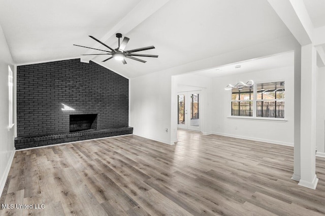 unfurnished living room with a fireplace, lofted ceiling with beams, ceiling fan, and light wood-type flooring