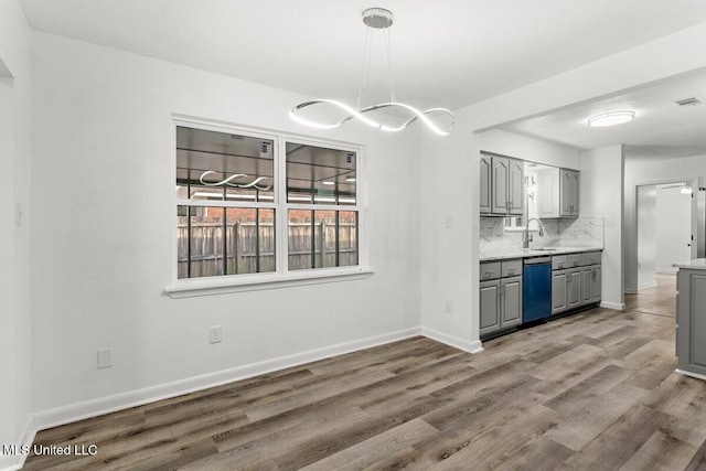 kitchen featuring sink, gray cabinetry, wood-type flooring, decorative backsplash, and stainless steel dishwasher