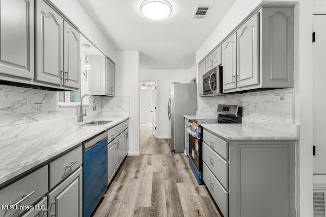 kitchen with stainless steel appliances, light hardwood / wood-style floors, sink, and gray cabinetry