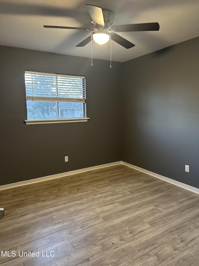 empty room with ceiling fan, wood-type flooring, and a textured ceiling