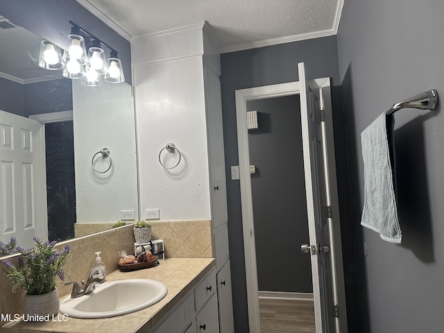 bathroom with hardwood / wood-style flooring, vanity, tasteful backsplash, ornamental molding, and a textured ceiling