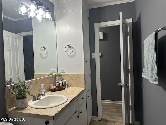 bathroom with tasteful backsplash, vanity, a notable chandelier, and ornamental molding