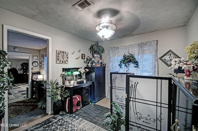 miscellaneous room with ceiling fan and a textured ceiling