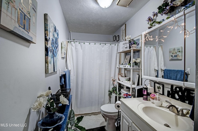 bathroom with vanity, toilet, and a textured ceiling