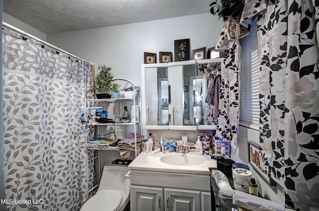 bathroom with vanity, toilet, and a textured ceiling