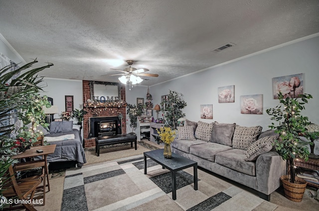 carpeted living room featuring ceiling fan, ornamental molding, a fireplace, and a textured ceiling